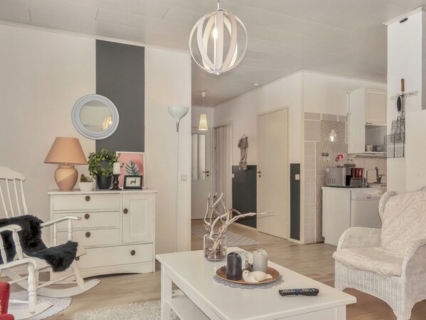 A living room with a white sofa, a white coffee table with decorative items, a white dresser, and a mirror.