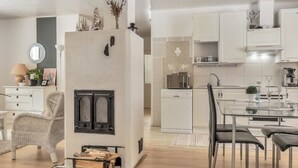 A modern kitchen with white cabinets, a central island, and a built-in wood stove.