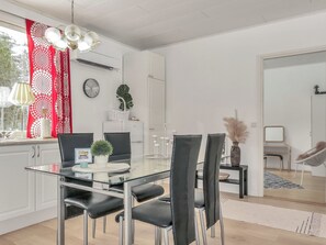 A modern dining area with a glass table, black chairs, and a red patterned curtain.