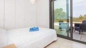 Ein Schlafzimmer mit Bett, Kleiderschrank und einem Balkon mit Gartenmöbeln.