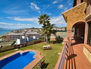 Ein Poolbereich mit Blick auf das Meer und eine Stadtlandschaft im Hintergrund.