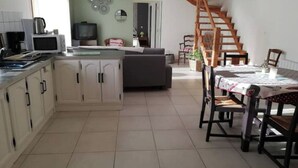 A kitchen with a dining area, a staircase, and a living room. - The deer house (Plouigneau)