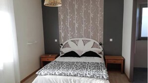 A modern bedroom with a bed, two nightstands, a woven light fixture, and a patterned wallpaper. - The deer house (Plouigneau)