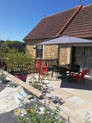A patio with outdoor furniture, a stone wall, and a tiled roof. - The Deer House (Plouigneau)