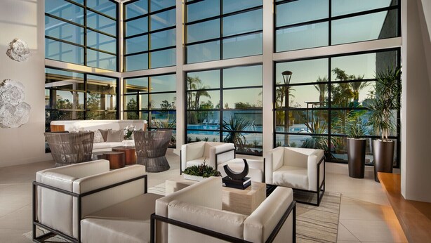 A spacious living area with large windows, modern furniture, and a view of a pool.