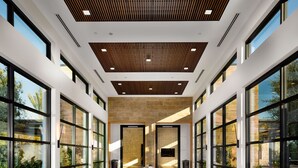 A modern interior with large windows, a central seating area, and a wooden ceiling.