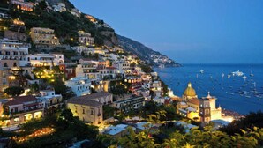 A coastal town with buildings along the hillside, a prominent church with a dome, and a view of the sea with boats. - Carla's House-Apartment The Olive Tree (Ravello)