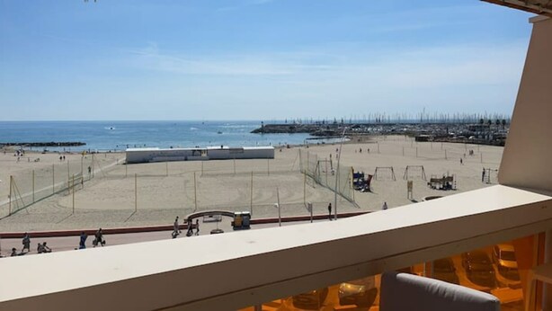 A beach view from a balcony with a clear sky, sandy beach, and a distant pier. - L'HORIZON -Apartment 1st line sea view Class3* (Palavas-les-Flots)