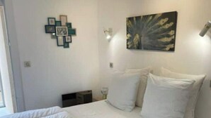 A bedroom with a large bed, a bedside table, a wall-mounted picture, and a small bedside lamp. - L'HORIZON -Apartment 1st line sea view Class3* (Palavas-les-Flots)