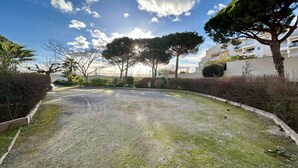 Un camino de grava que conduce a una zona residencial con árboles y un edificio al fondo.