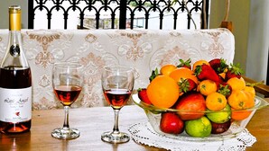 Une table avec une bouteille de vin, deux verres et un saladier de fruits.