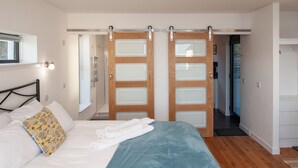 A bedroom with a bed, a window, and a sliding door. - Croft 7 Geary Self Catering Studio (Waternish)