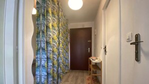 A narrow hallway with a wooden floor, a door at the end, and a small table with a cup and a plate. - Cozy 2-Room Apartment with Pool, Parking, and Near the Beach (Sainte-Maxime)