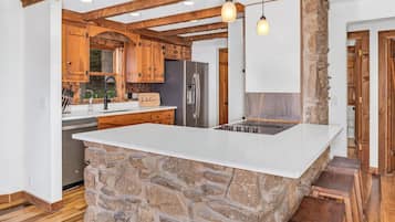 A kitchen with a stone island, wooden cabinets, and a built-in refrigerator.