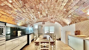 A kitchen with a brick ceiling, a dining table with chairs, and modern appliances.