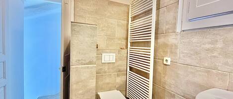A bathroom with a toilet, a radiator, and a sink.