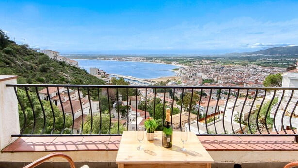 A balcony with a table, two wine glasses, and a bottle of champagne.