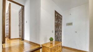 A hallway with wooden doors, a wooden dresser, and a tiled floor.