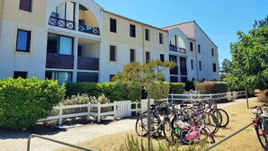 A multi-story building with balconies, a fenced courtyard, and bicycles parked outside. - Cozy 1-Bedroom Apartment with Terrace, Steps from Saint-Georges-de-Didonne Beach (Saint-Georges-de-Didonne)