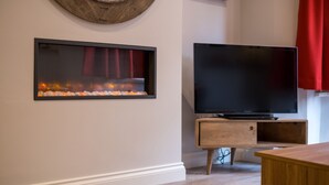Un salon moderne avec une cheminée, un téléviseur à écran plat posé sur un meuble en bois et une table basse en bois.