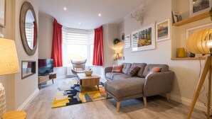 Un salon moderne avec un canapé, un téléviseur, une lampe et un grand miroir.