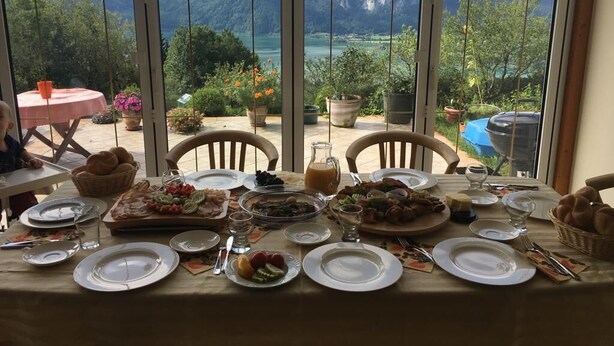 Ein Esstisch, gedeckt für eine Mahlzeit, mit Blick auf Berge durch große Fenster.