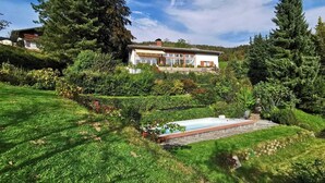 Ein Haus mit Swimmingpool, umgeben von üppiger Vegetation und Bäumen.