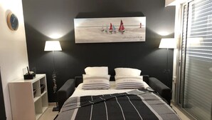 Een slaapkamer met een bed, twee nachtkastjes, een lamp, een schilderij en een raam met jaloezieën.