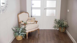 Un couloir avec une chaise en bois, une plante en pot et une porte dont les panneaux sont en verre dépoli.