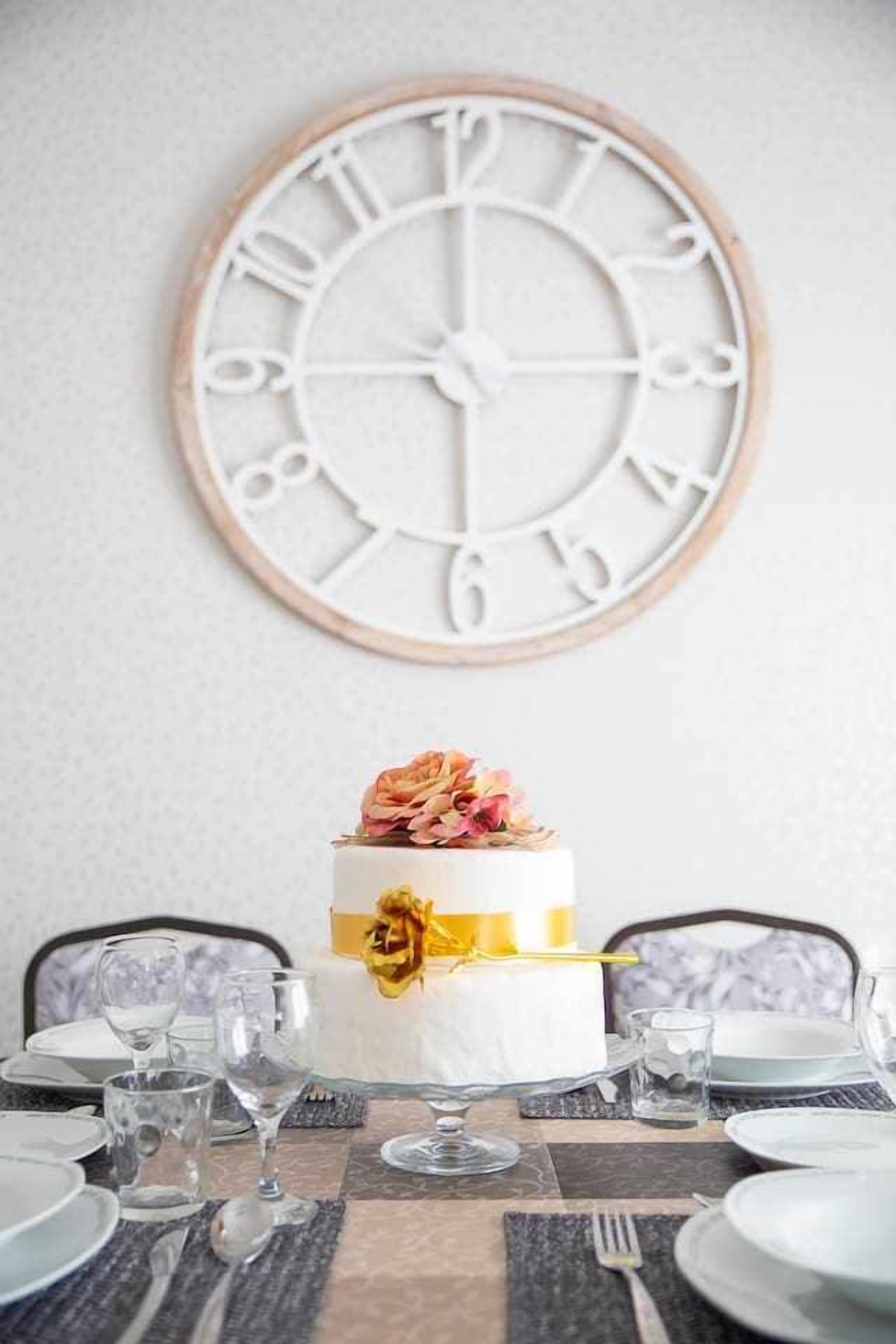Una mesa de comedor dispuesta con platos, vasos y un pastel decorado con una flor.