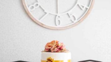 A dining table set with plates, glasses, and a cake with a flower decoration.