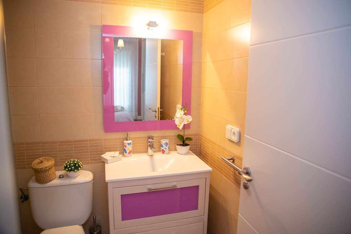 A bathroom with a toilet, sink, and mirror.