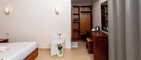 A hotel room with a bed, a small refrigerator, a desk, and a wardrobe.
