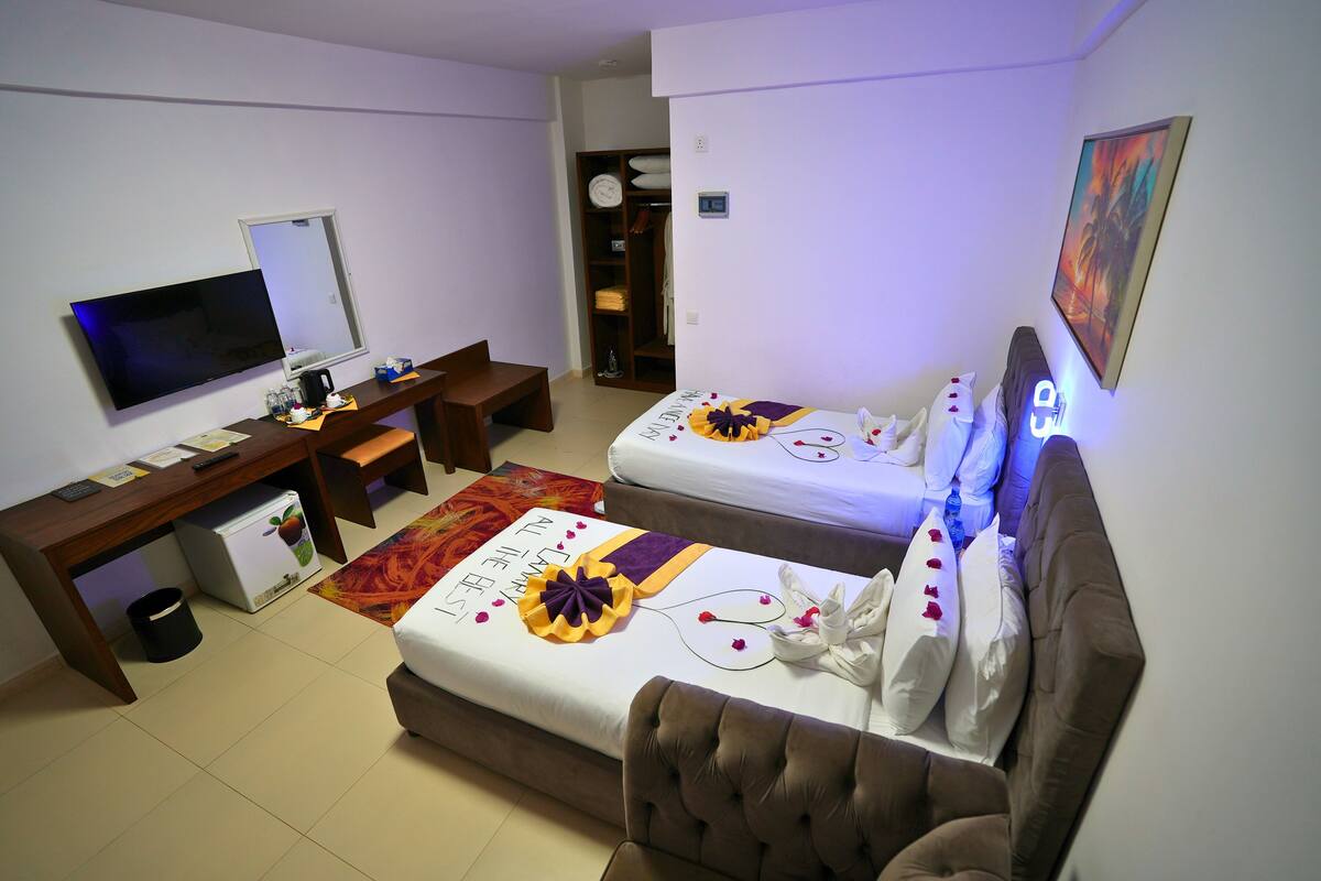 Una habitació d'hotel amb un llit, una taula de treball, una televisió i un armari.
