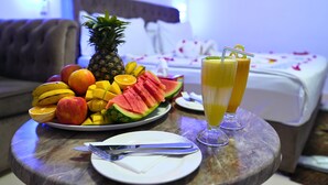 Une table de petit-déjeuner avec des fruits, un ananas et deux verres de jus d’orange dans une chambre d’hôtel.