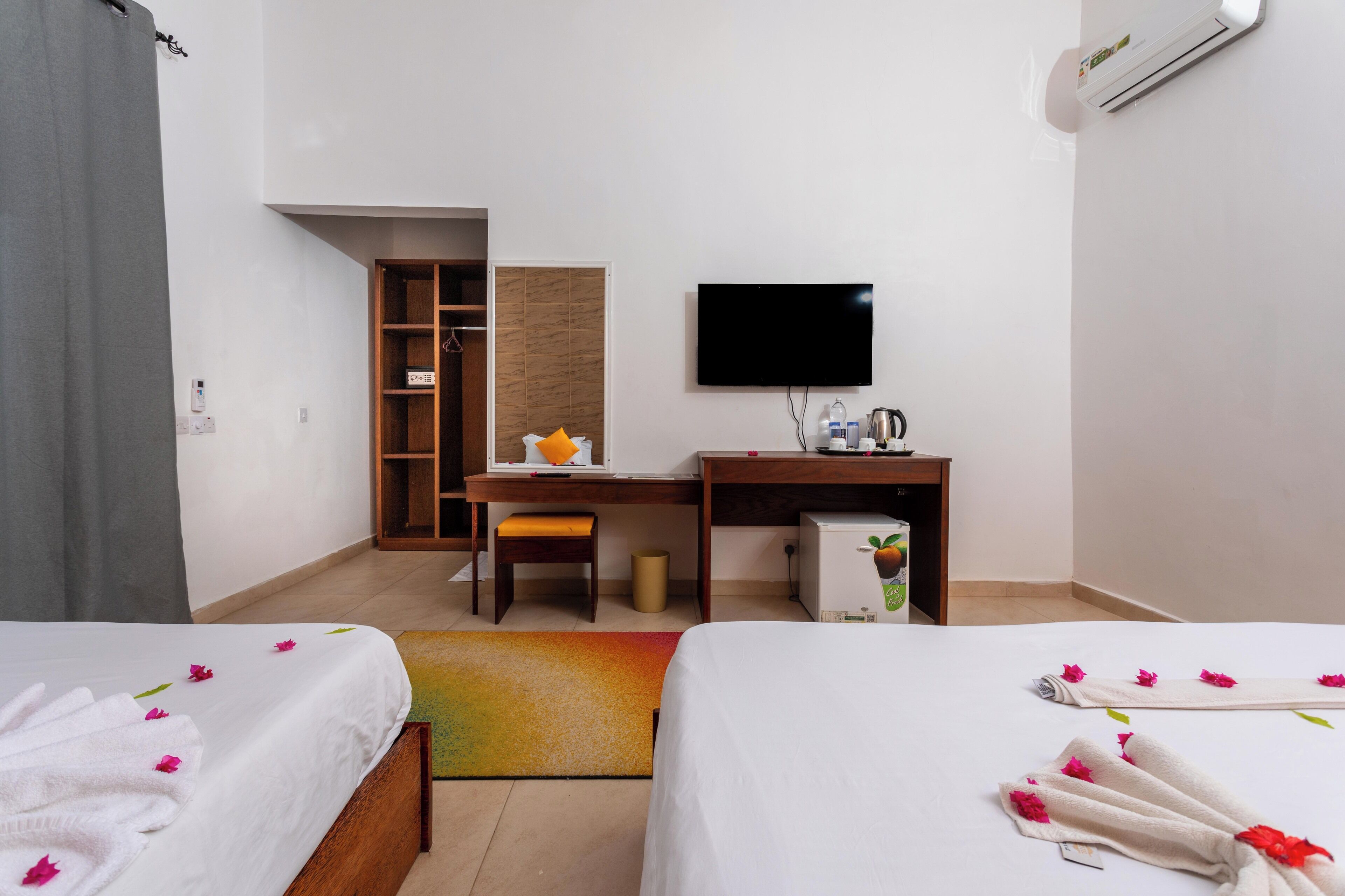 Ein Hotelzimmer mit zwei Betten, einem Schreibtisch, einem Fernseher und einer Minibar.