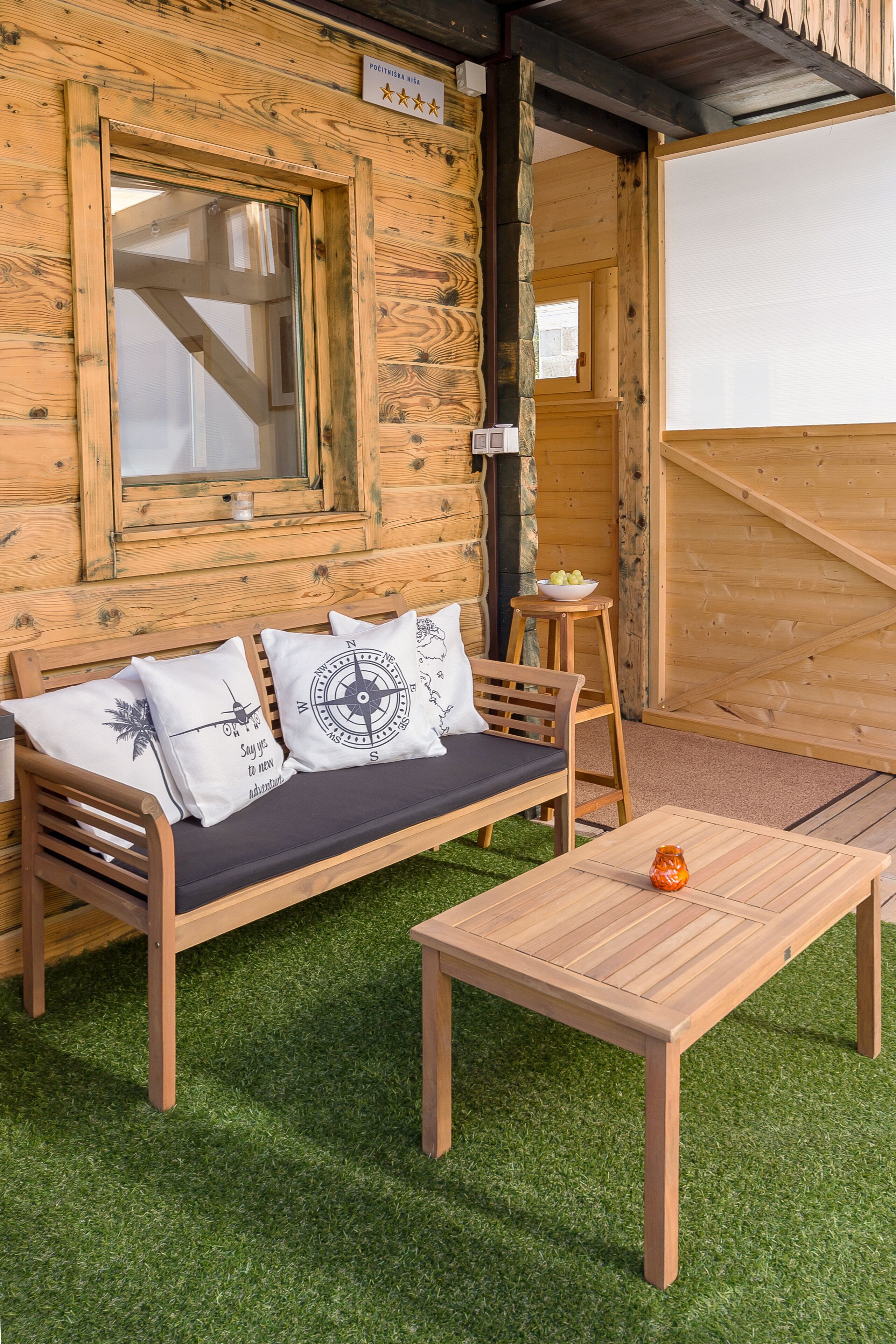 Eine Holzhütte mit einer Couch und einem Tisch, umgeben von Kunstgrün.