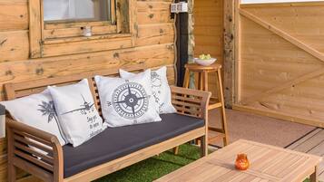 Eine Holzhütte mit einer Couch und einem Tisch, umgeben von Kunstgrün.