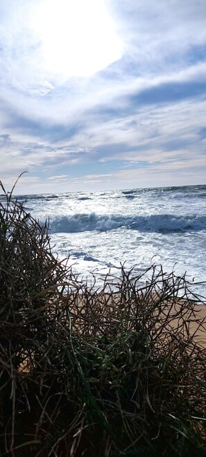 Ein Strand mit Wellen und bewölktem Himmel.