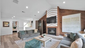 A modern living room with a fireplace, a sofa, a coffee table, and a television. - Lakefront Getaway ☀️ Quiet Canal - Park Your Boat 🚤 4 Bed Townhouse by EverSan Cooper Getaways (Montgomery)