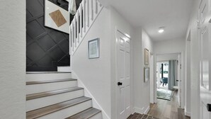 A modern staircase with wooden steps and white walls, leading to a door with a picture frame. - Lakefront Getaway ☀️ Quiet Canal - Park Your Boat 🚤 4 Bed Townhouse by EverSan Cooper Getaways (Montgomery)