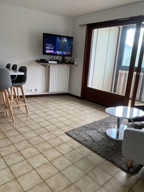 Relax in this stylish living room with a flat-screen TV, dining area, and comfortable seating for four.