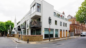A modern building with a balcony, large windows, and a brick wall. - Abstract Perspective, by Veeve (London)