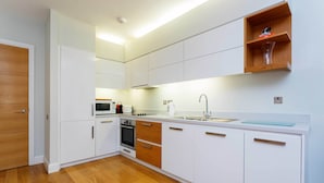 A modern kitchen with white cabinetry, a wooden floor, and a built-in oven. - Abstract Perspective, by Veeve (London)