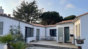 A courtyard with a wooden deck, outdoor seating, and a bicycle. - Vacation home with jacuzzi 5 minutes from the beach (LE BOIS PLAGE EN RE)