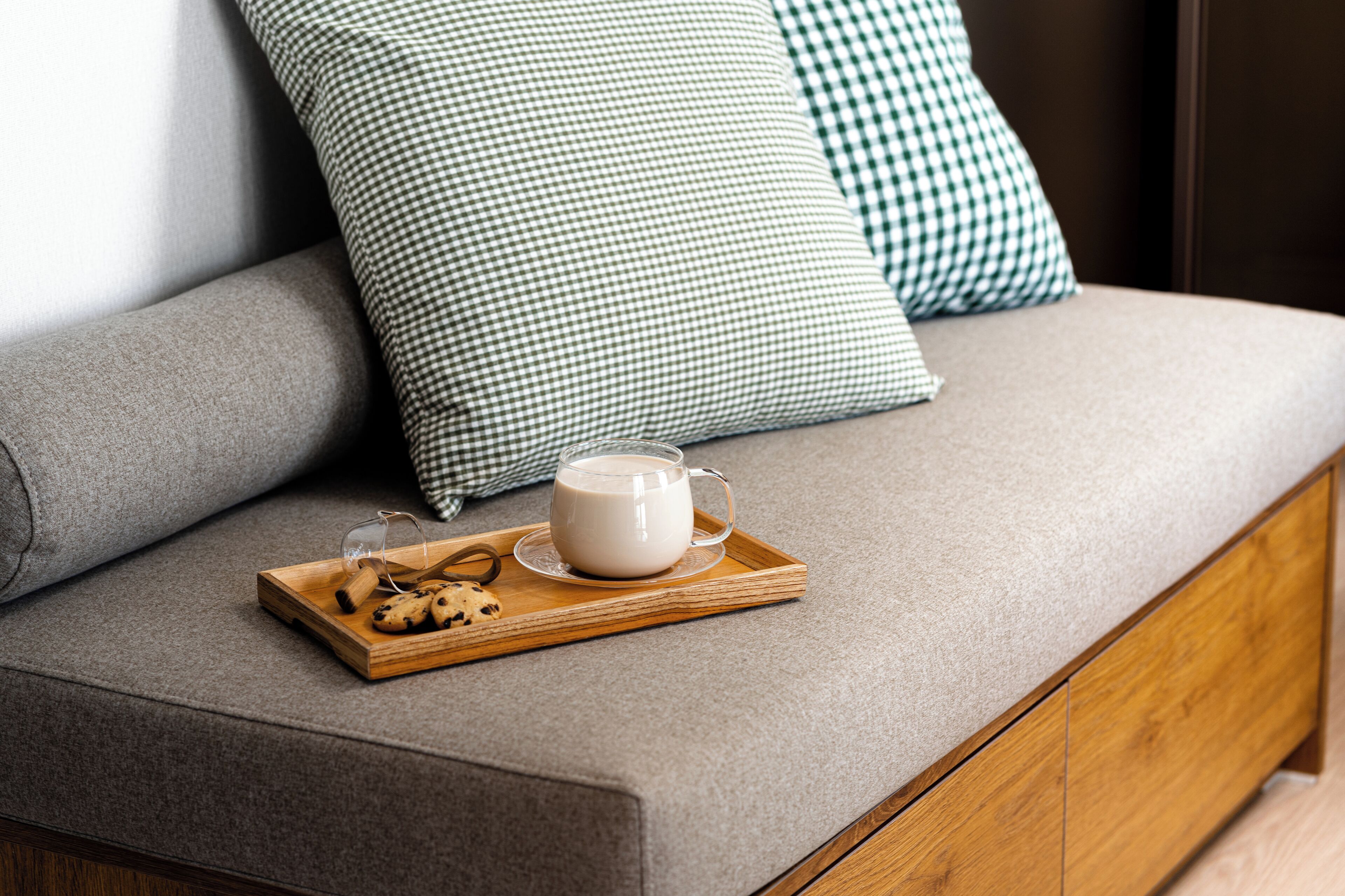 A sofa with a tray of cookies and a mug of coffee.