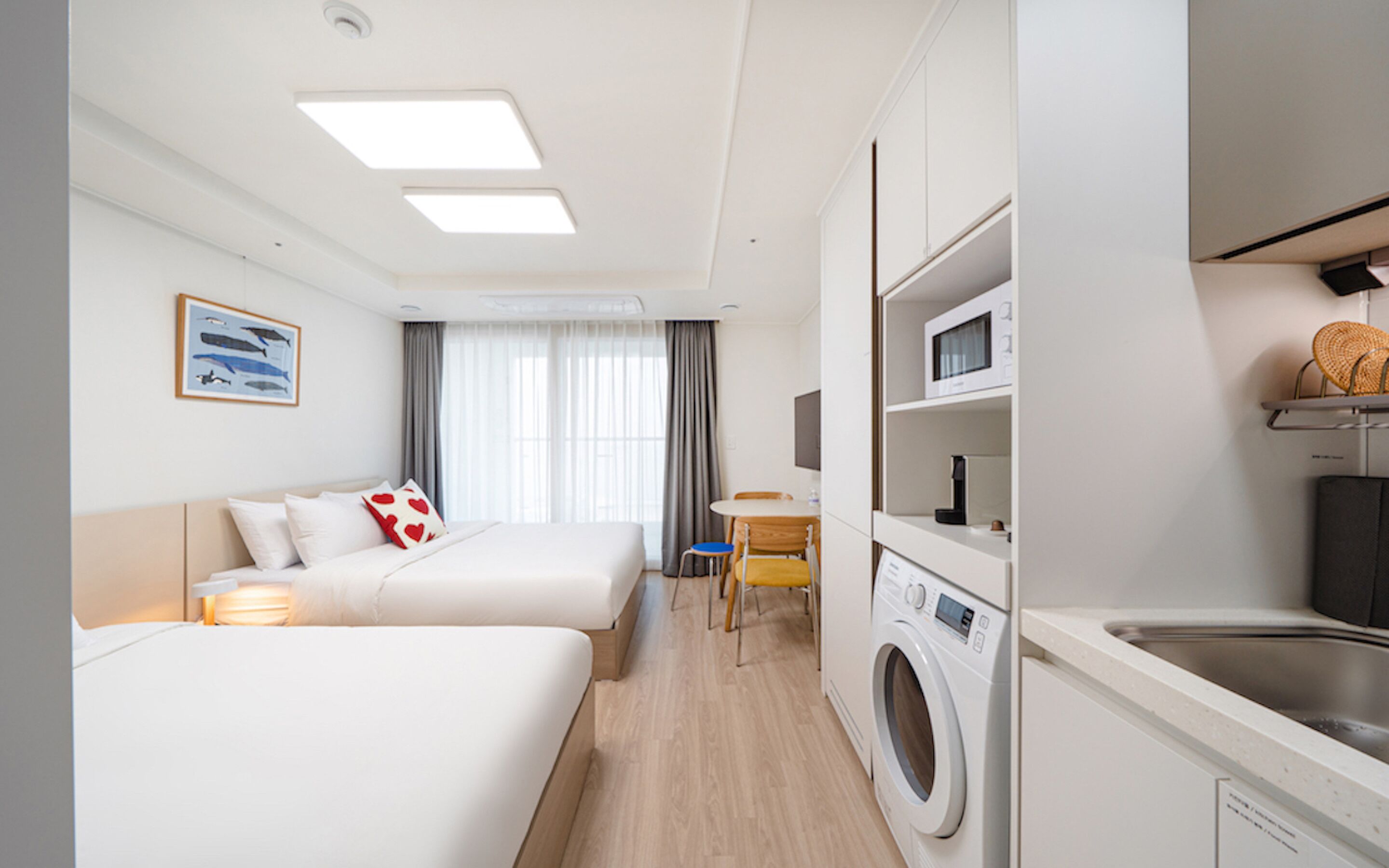 Une chambre d’hôtel avec deux lits, un lave-linge, un four à micro-ondes et une petite table.