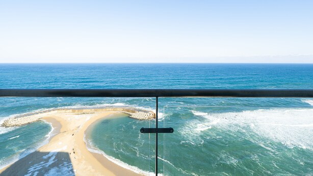 Uitzicht op het strand vanaf een balkon met een balustrade.