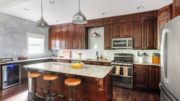 A modern kitchen with dark wooden cabinets, stainless steel appliances, and a central island with stools.