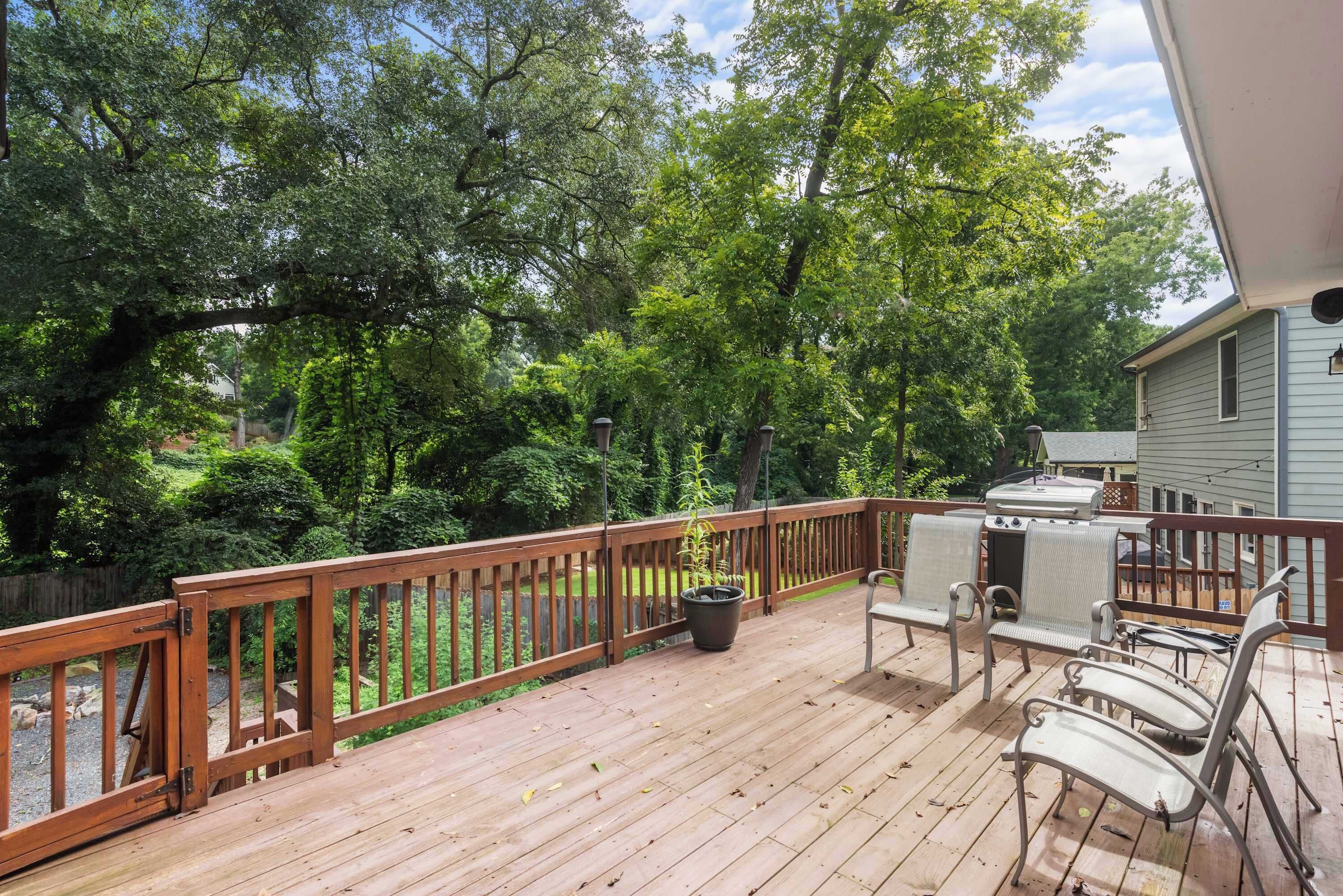 A wooden deck with a railing, surrounded by lush greenery and trees.